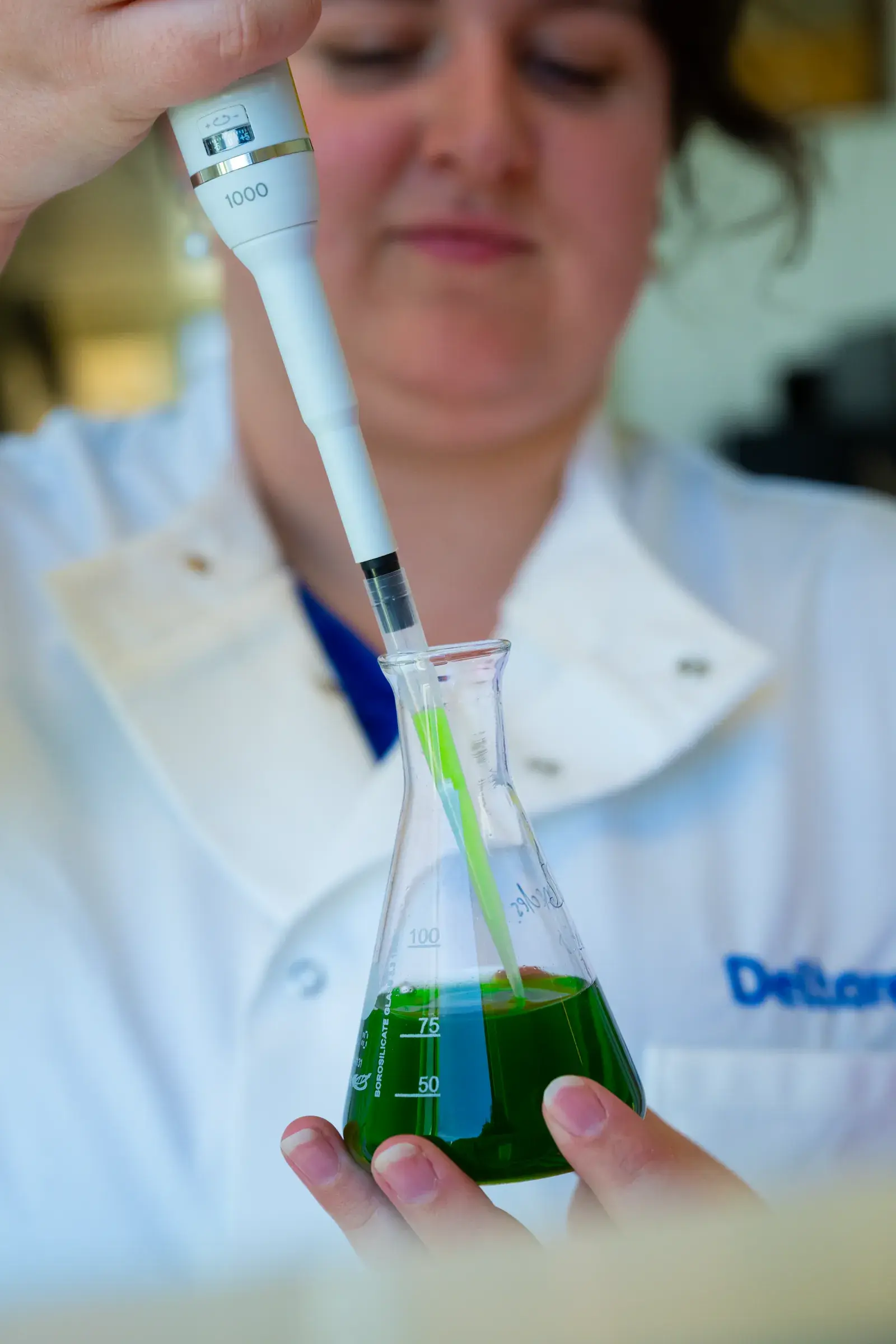 Researcher pipetting a green algae sample into a flask