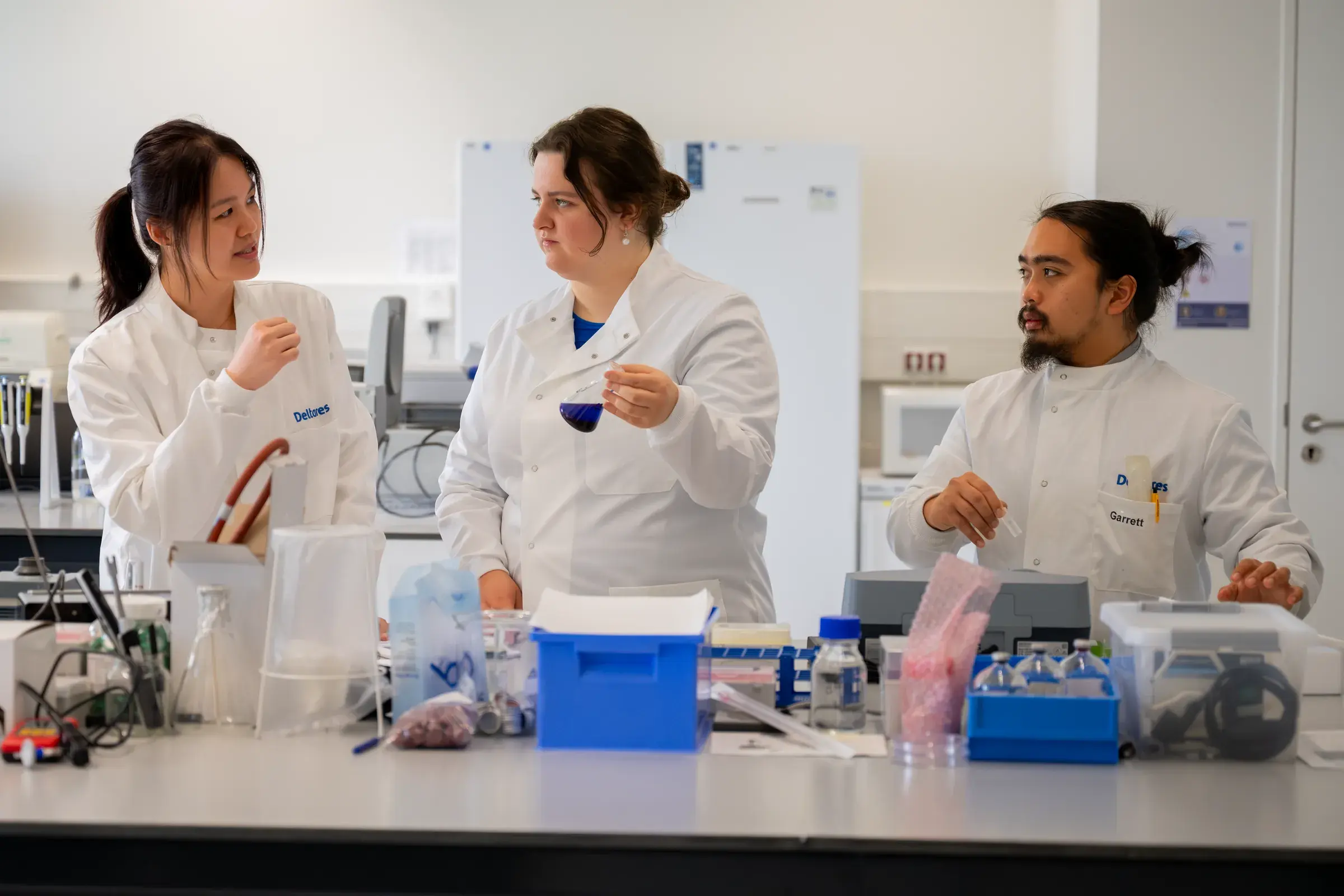 Algaenius team in lab coats discussing samples in the laboratory